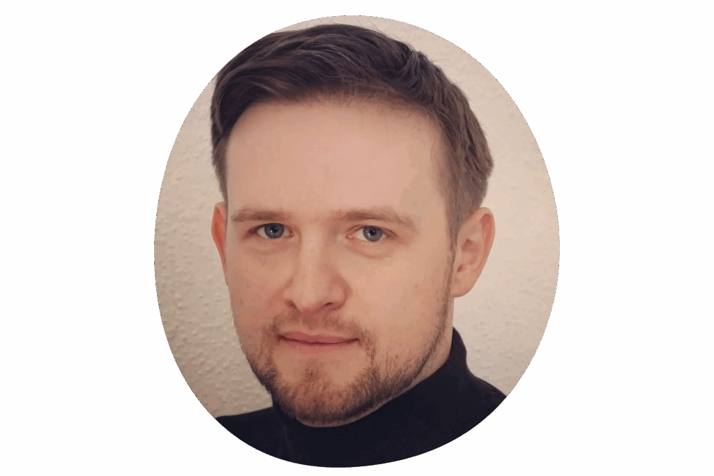 Person mit kurzen, dunklen Haaren vor einem hellen, einfarbigen Hintergrund.