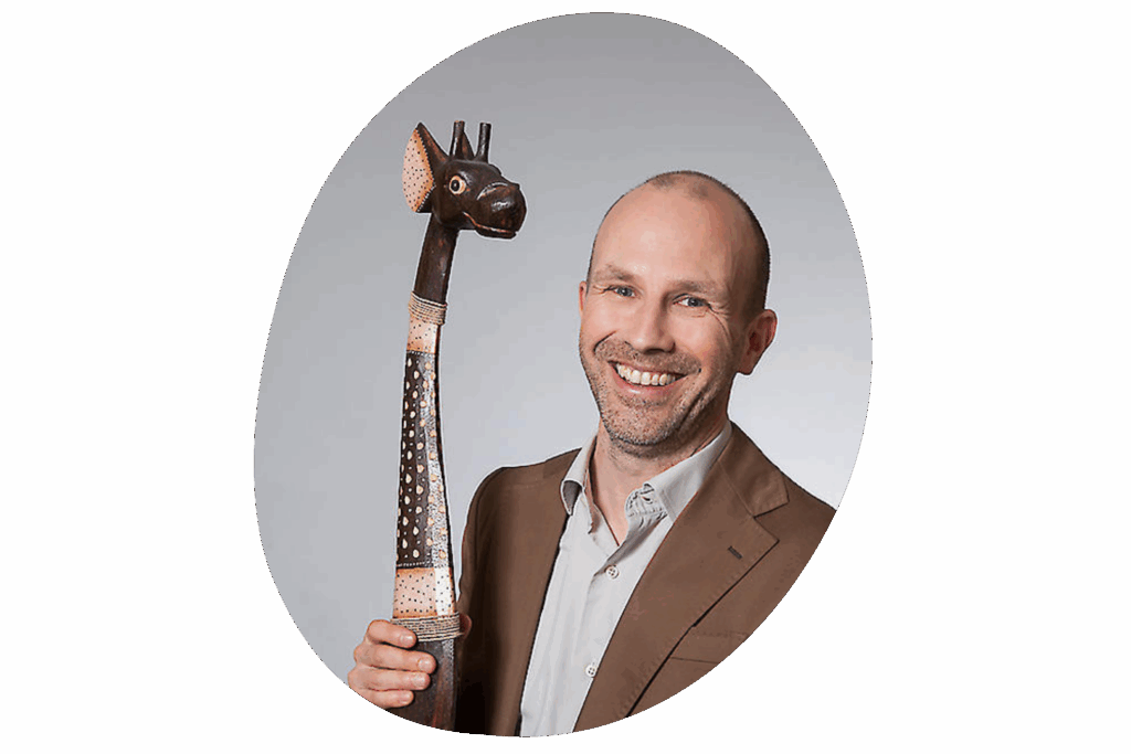 Person mit kurzen, dunklen Haaren vor einem hellen, einfarbigen Hintergrund.