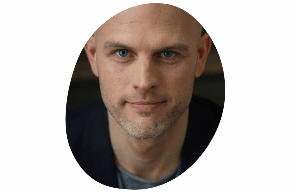 Nahaufnahme des Gesichts eines Mannes, der eine Glatze trägt und einen dunklen Anzug.