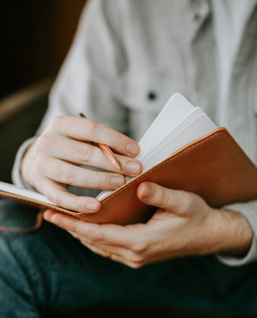 Hände die Notizbuch und Bleistift halten