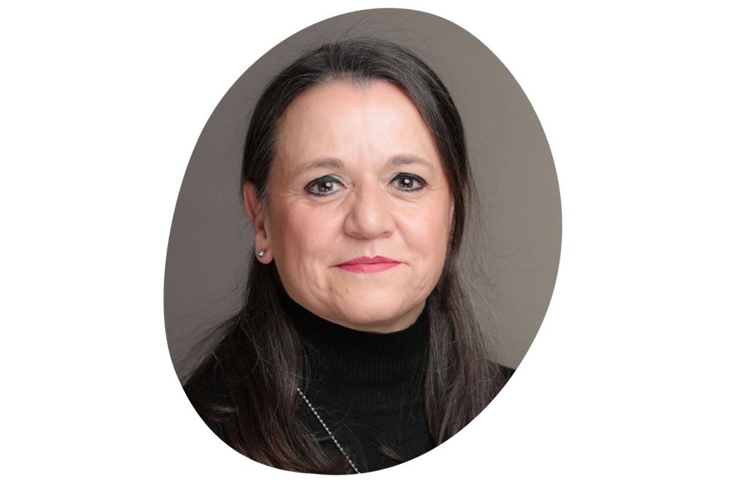 Frau mit langen dunklen Haaren in schwarzem Rollkragenpullover vor grauem Hintergrund.