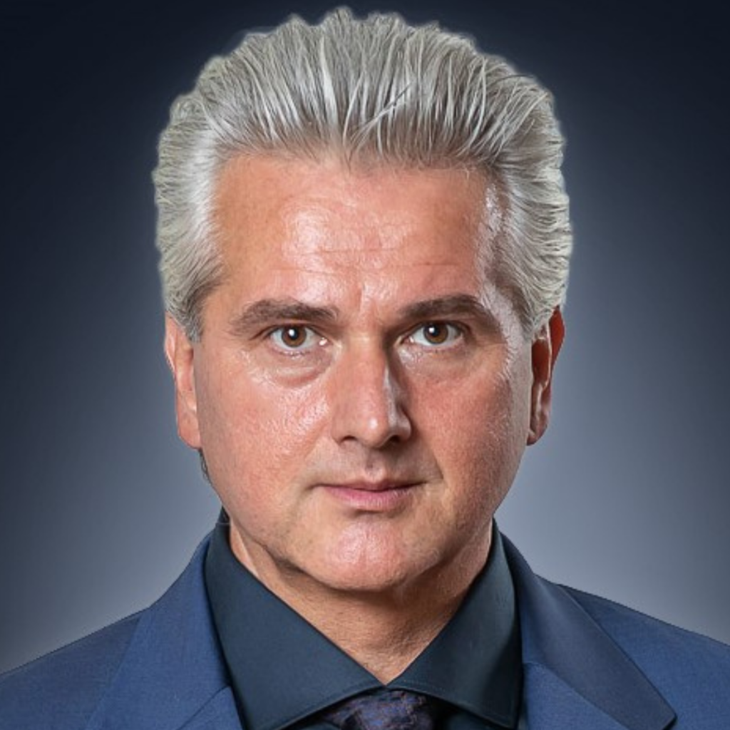 Porträt einer Person mit zurückgekämmtem, grauem Haar und dunklem Anzug vor dunklem Hintergrund