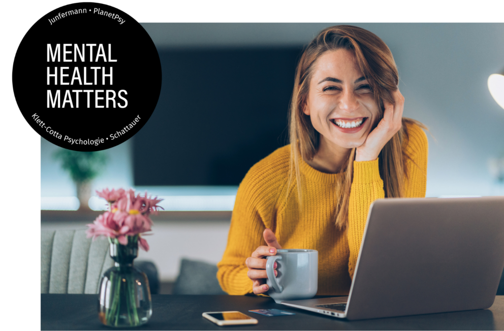 Frau mit langen braunen Haaren und gelben Pulli sitzt lächelnd mit Kaffeetasse am Tisch vor einem Laptop. Daneben ein Button mit der Aufschrit: "Mental Health Matters"