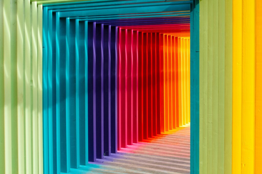 Farbenfroher Tunnel aus geometrischen Rahmen in Regenbogenfarben als Symbol für Neurodiversität, unterschiedliche Denkweisen und die unterstützenden Möglichkeiten von Künstlicher Intelligenz.
