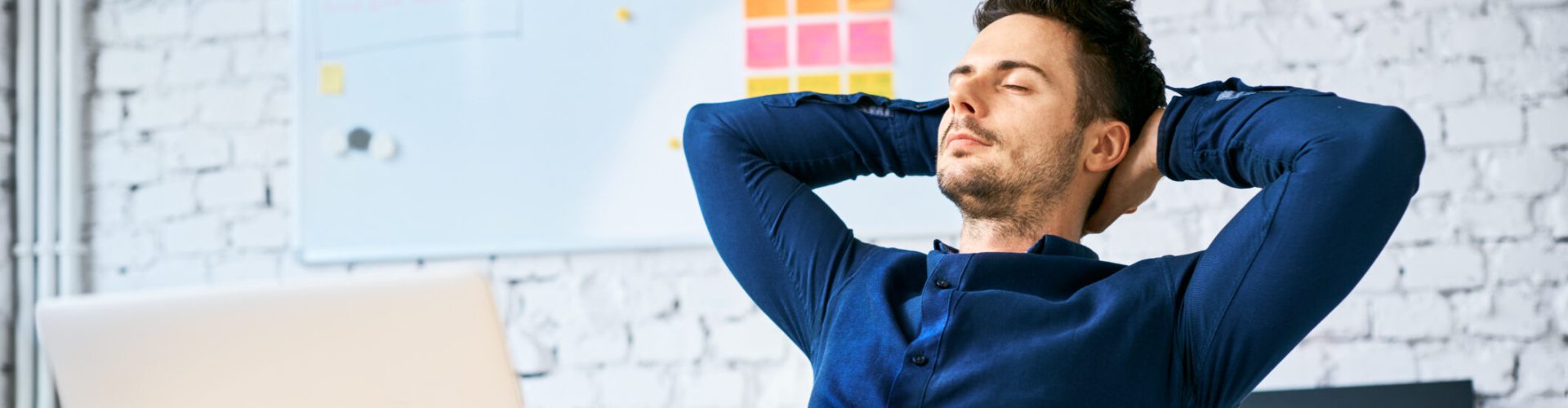 Businessman relaxing at work with hands behind head, eyes closed and coffee