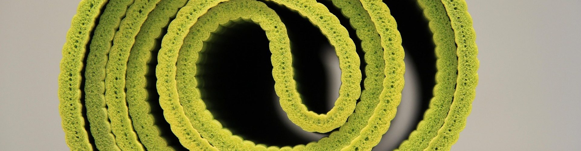 Eine zusammengerollte, grüne Yogamatte.